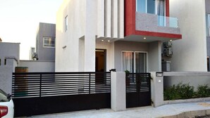 A modern two-story residential building with a black gate, a visible door, and a small balcony. - Modern 2 Bedroom Duplex - Gated Estate , 24/7 Security, Gym, Pool, Tennis Court (Tema)