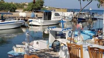 A waterfront restaurant with outdoor seating, boats docked nearby, and a clear view of the water.