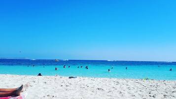 Une plage avec une eau d’un bleu limpide et un rivage sablonneux.