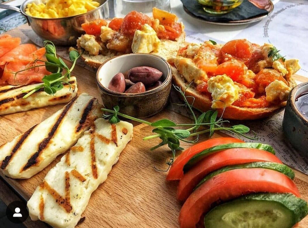 Diversos alimentos a la parrilla, entre ellos pan, tomates y un plato con huevos y tomates.