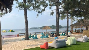Un área de descanso frente al mar con césped artificial verde, sillas de salón azules y vistas al océano.