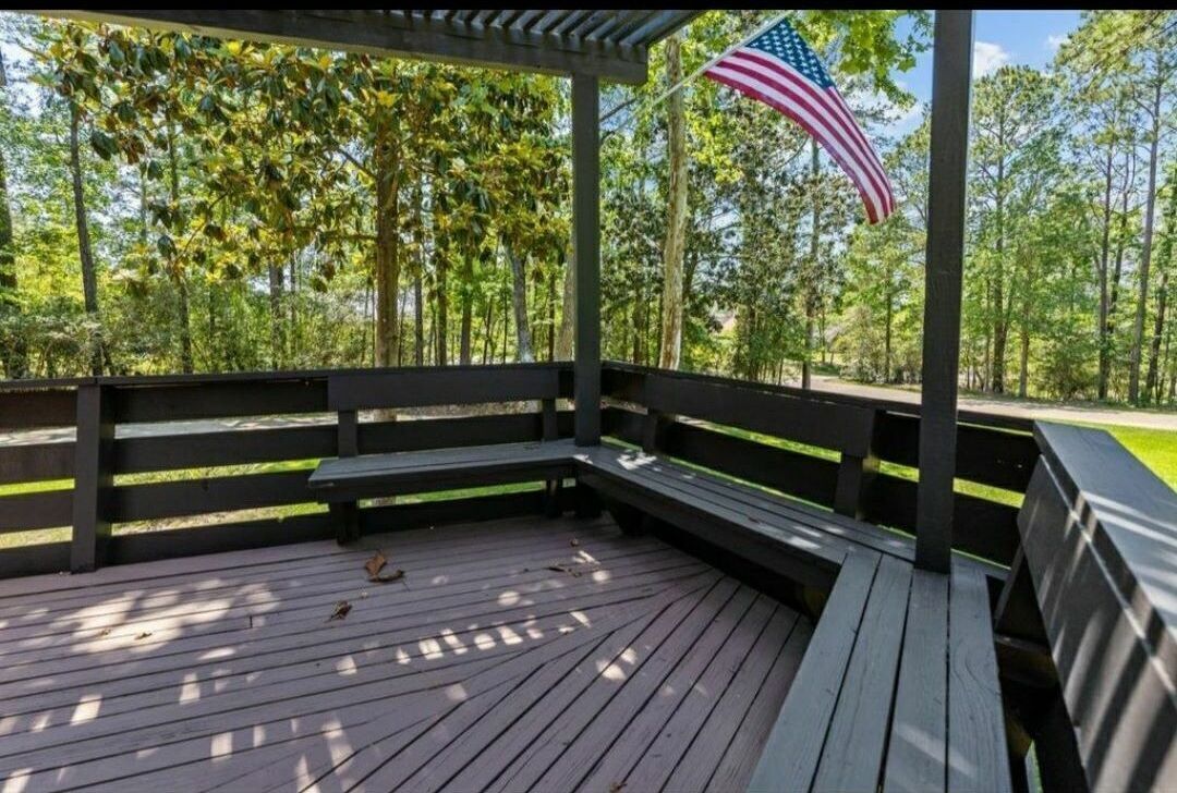 Un'area esterna coperta con un pavimento in legno, panche e una bandiera americana.