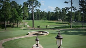 Un campo de golf con un césped bien cuidado, un sendero sinuoso y dos faroles de piedra.