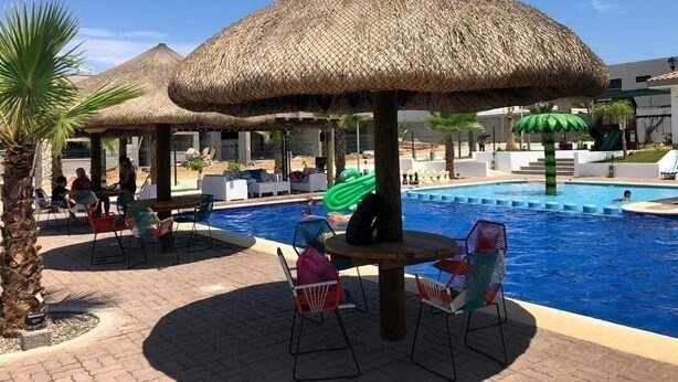 Ein Poolbereich mit Reetsonnenschirmen, Liegestühlen und einem Schwimmbecken.