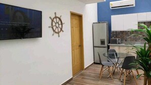Eine kleine, moderne Küche mit Kühlschrank, Mikrowelle und einer gefliesten Spritzschutzwand.