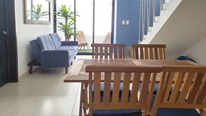 Ein modernes Wohnzimmer mit einem blauen Sofa, einem Holzesstisch und Stühlen.