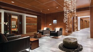 A modern lobby with wooden paneling, leather seating, and a unique bubble chandelier.