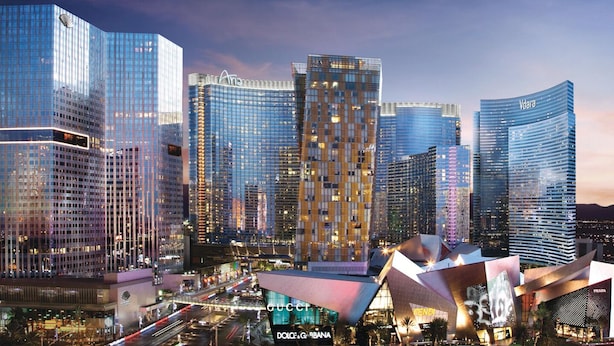 A modern cityscape with high-rise buildings, including a prominent curved structure with a Prada store.