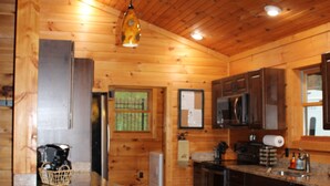 A wooden cabin interior with a kitchen featuring a central island, built-in appliances, and a hanging light fixture. - 2 Acres of pure paradise with amazing Mountain View’s!! Minutes from Emory&Henry (Meadowview)