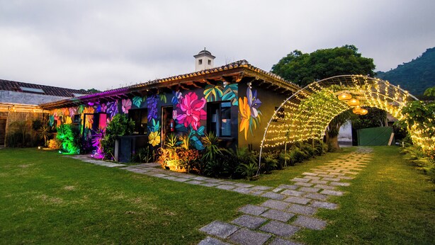 Un edificio con murales coloridos, un sendero de piedra y un arco decorativo.