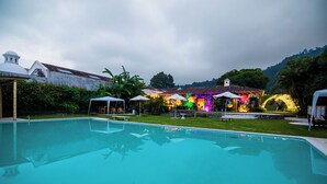 Una piscina con vistas despejadas del entorno, incluyendo un edificio con luces de colores y una colina al fondo.
