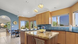 A modern kitchen with a central island, wooden cabinets, and large windows.