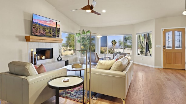 A spacious living room with a fireplace, comfortable seating, a television, and large windows offering a view of the outdoors.