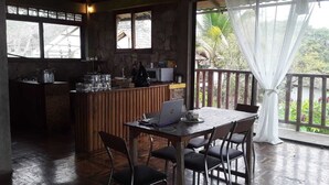 A rustic kitchen with a wooden table and chairs, a laptop, and various kitchen items.
