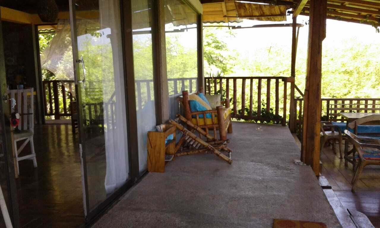 A covered porch with a wooden swing chair and a dining table.