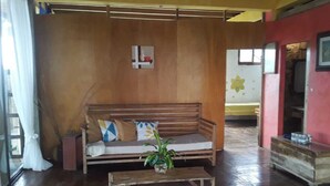 A wooden sofa with cushions, a small wooden table with a plant, and a wooden bench.
