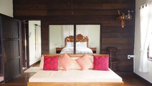 Een slaapkamer met een houten bedframe, een grote spiegel en een nachtkastje.