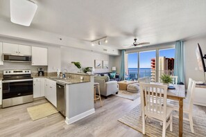 Enjoy ocean views from the large window in this spacious living area with a kitchen, dining space, and comfortable seating.