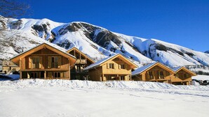 Um hotel de estilo chalé de madeira, com várias divisões, emoldurado por montanhas cobertas de neve.