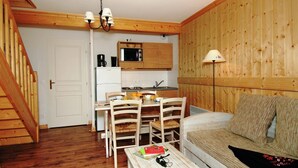 Um espaço compacto com cozinha compacta, área de refeições e espaço para sentar.