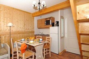 Una cocina compacta con armarios de madera, microondas, cafetera y refrigerador.