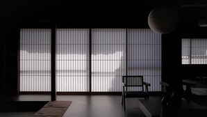 Una habitación con suelo de tatami, una mesa baja, una silla y puertas correderas de papel.