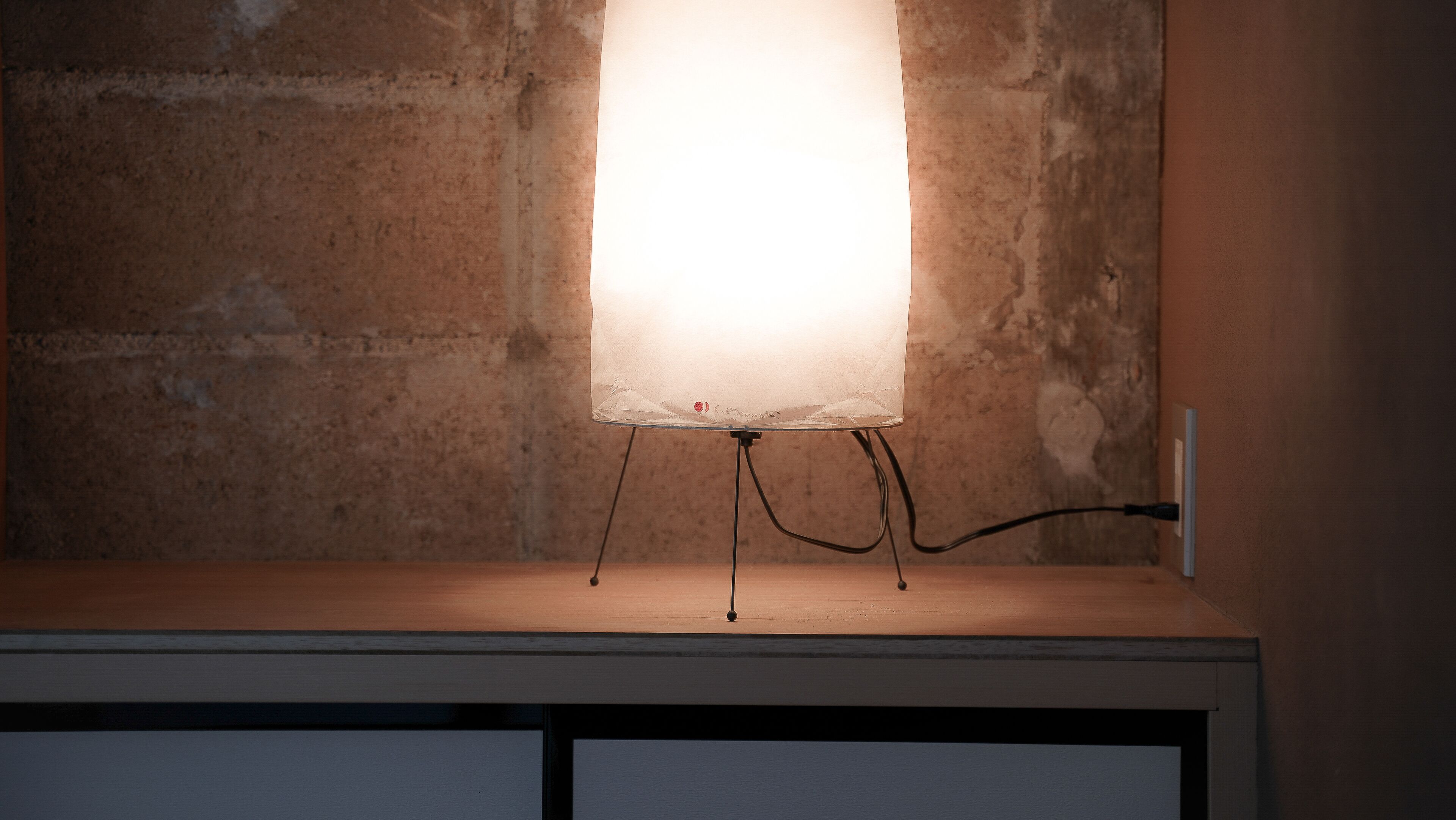 A table lamp with a clear shade, mounted on a wall with a rough texture.