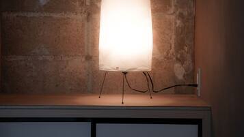 A table lamp with a clear shade, mounted on a wall with a rough texture.