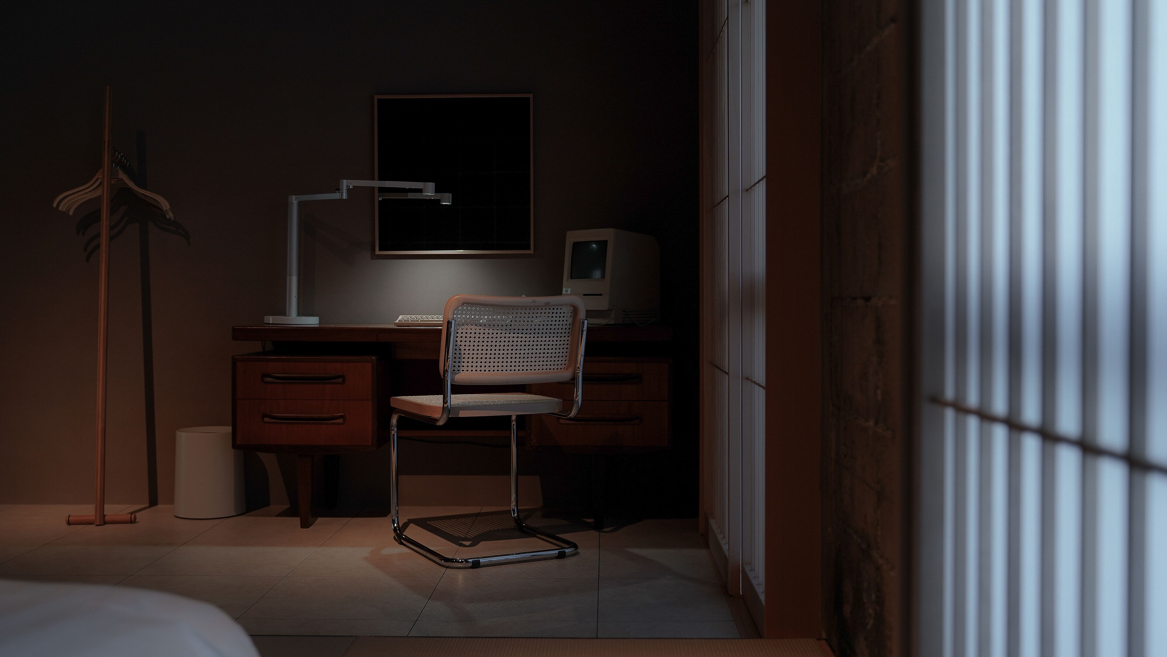 Une pièce faiblement éclairée, avec un bureau, une chaise et un lampadaire.
