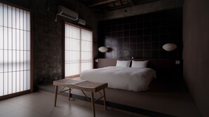 Un dormitorio moderno con una cama grande, una mesa de madera y vistas al exterior a través de puertas shoji.