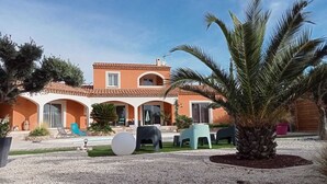 Een villa in mediterrane stijl met een betegeld dak, een terras en een grindpad.