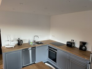 A modern kitchen with a dishwasher, oven, and a coffee maker.