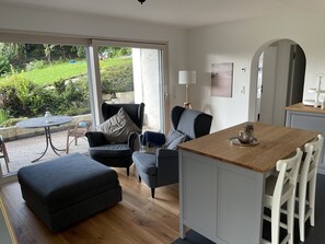 A modern kitchen with a wooden countertop, white cabinets, and a dining area with a table and chairs.