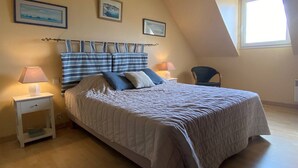 A bedroom with a bed, two bedside tables, a chair, and a window.