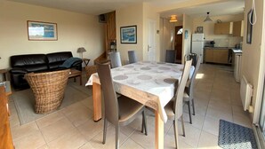 A compact living space with a dining area, kitchen, and a living room with a sofa and a lamp.