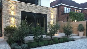 Een modern huis met een gevel van natuursteen, een groot raam en een grindpad.