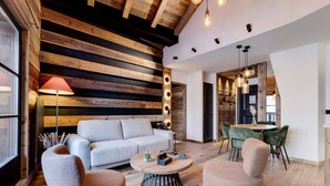 A modern living room with a sofa, two armchairs, a coffee table, and a dining area with chairs.