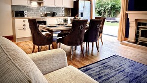Une cuisine moderne avec des armoires blanches, un four à micro-ondes encastré et un coin repas comprenant une table et des chaises en bois.