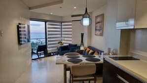 A modern kitchen with a dining area, large windows, and a view of the sea.
