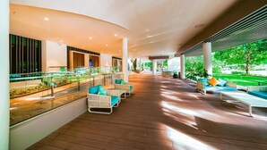 A covered outdoor area with seating and a glass railing overlooking a garden.