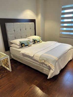 A bed with a tufted headboard, white bedding, and decorative pillows. - Sea view brand new one bedroom apartment in 5 star Tambuli  Resort & spa (Lapu-Lapu City)