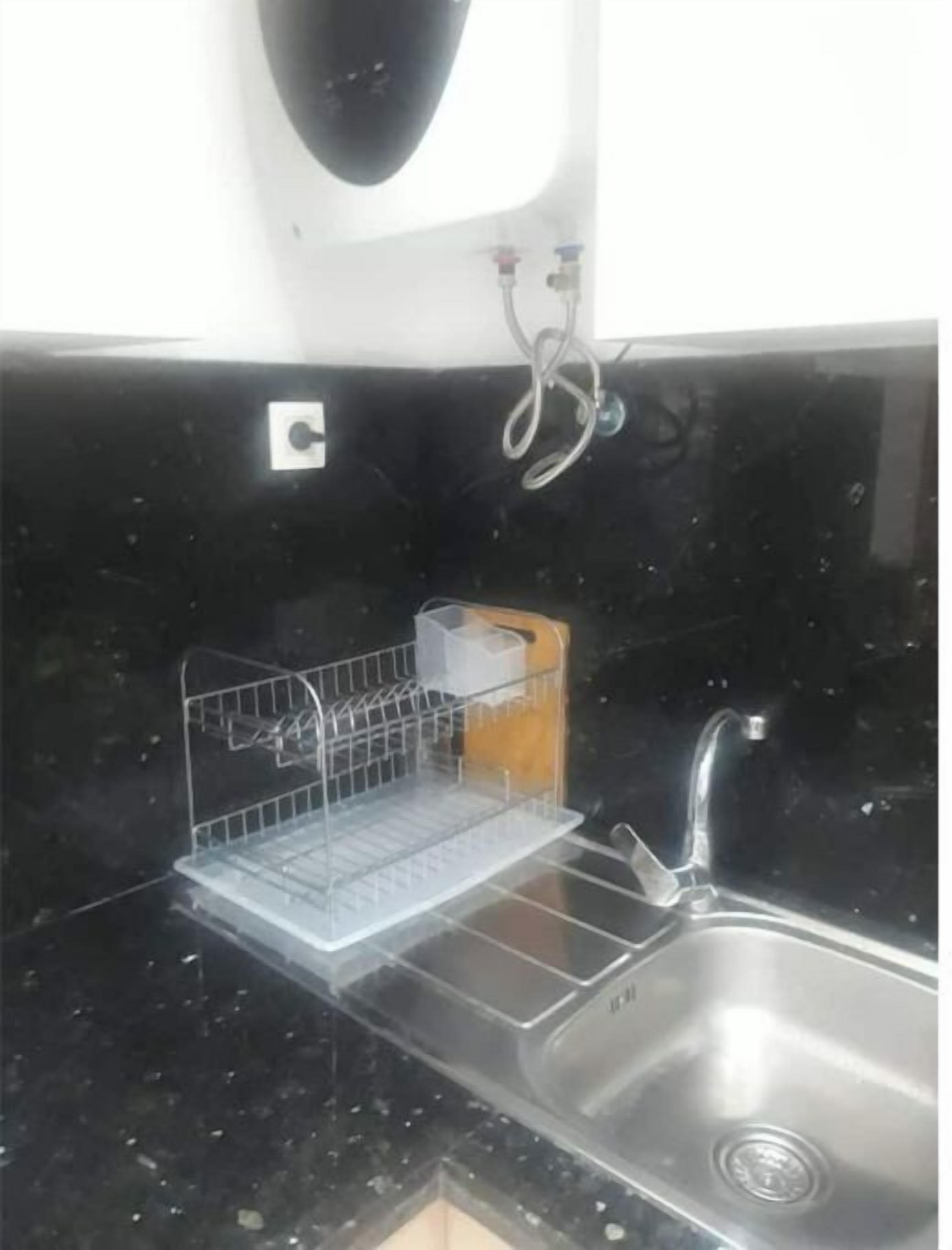 A kitchen with a stainless steel sink, a dish rack, and a soap dispenser.