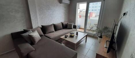 A modern living room with a sectional sofa, a coffee table, and a TV on a wooden stand.