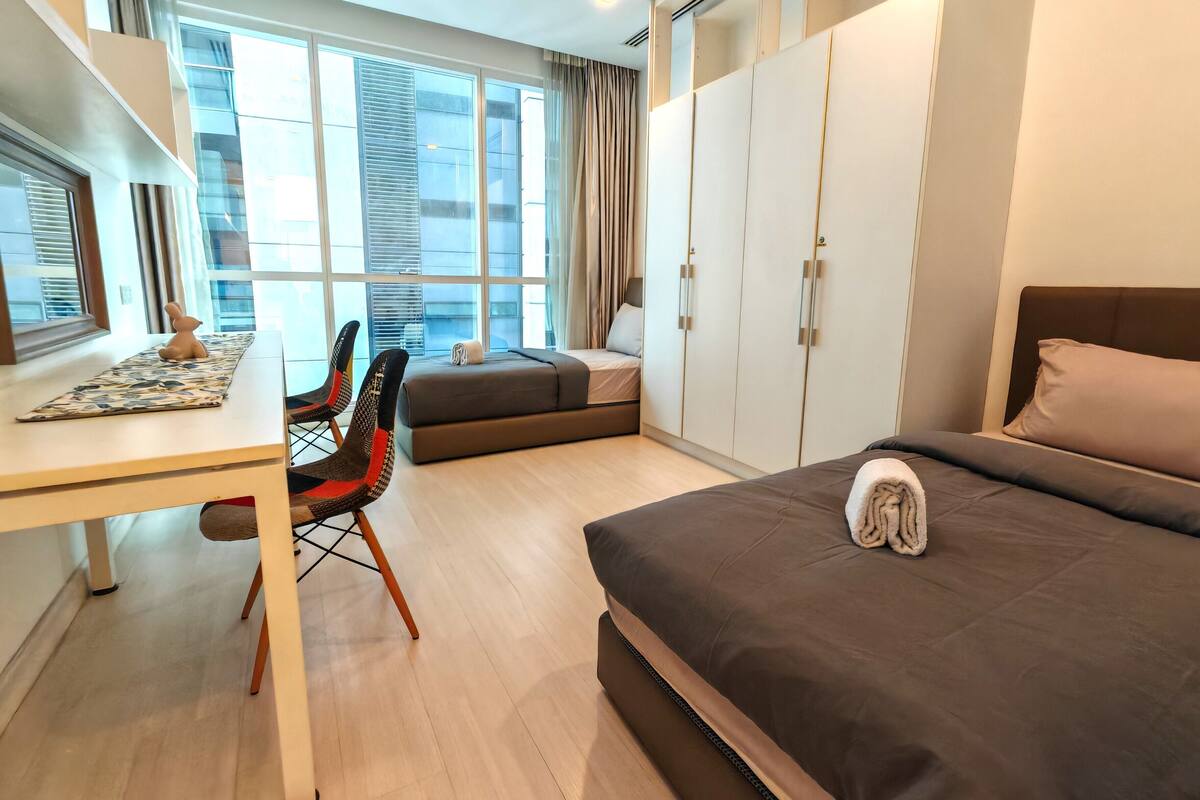Una habitación de hotel moderna con cama, escritorio, silla y armario.