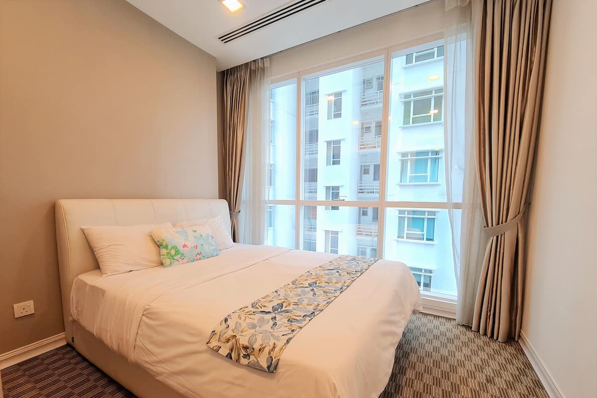 Una habitación de hotel con una cama grande, una ventana con cortinas y vistas a edificios.