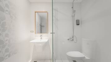 A modern bathroom with a glass shower enclosure, a white sink, and a toilet.