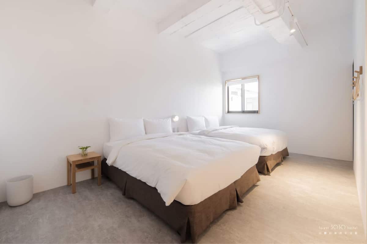 Un dormitorio minimalista con una cama grande, una mesita de noche pequeña y una ventana.