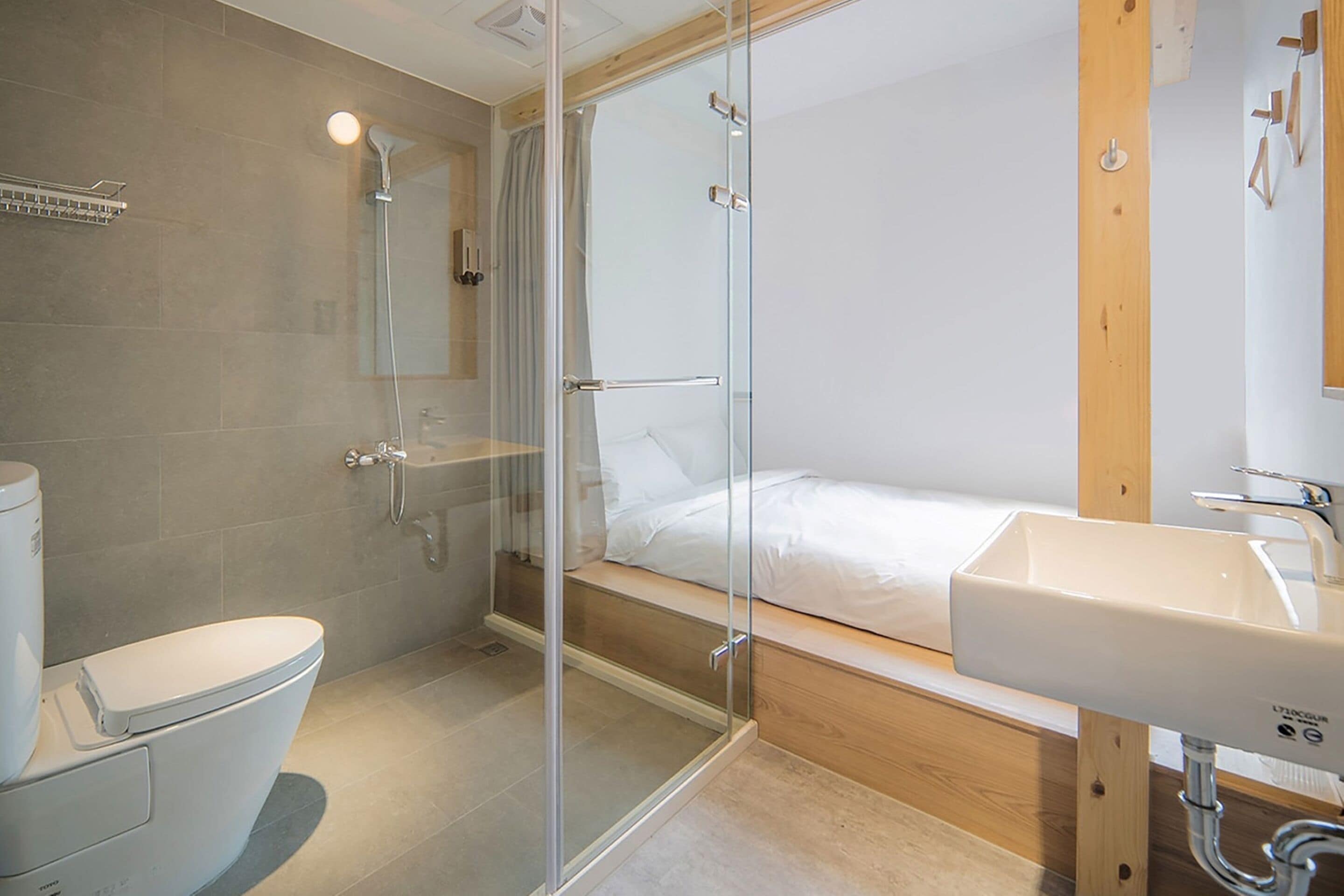 A modern bathroom with a glass-enclosed shower, a toilet, and a sink.