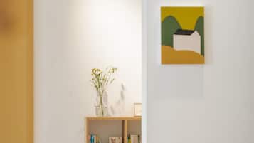 A room with a bookshelf, a framed picture on the wall, and a vase with flowers on a table.
