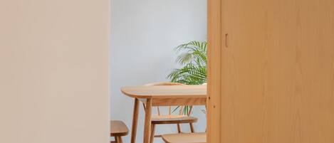 Una mesa de madera con un banco, una planta en maceta y una puerta de madera.
